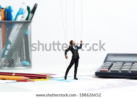 businessman puppet doll is on the desk, past the stationery items
