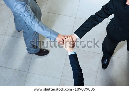 team of three businessmen clasped her hands together, a symbol of teamwork