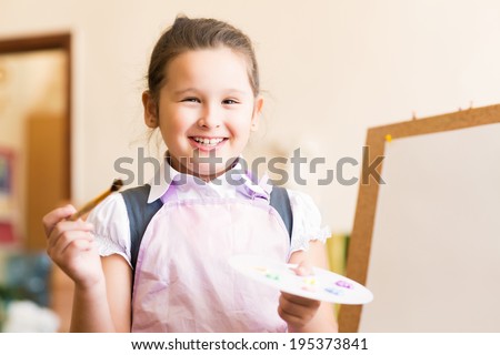 Portrait of Asian girl in apron interested in painting at an art school