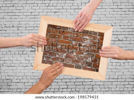 Close up of human hands holding wooden frame with brick texture