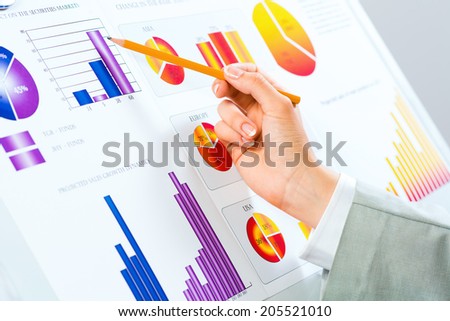 female hand pointing pen on financial charts, paper work in the office