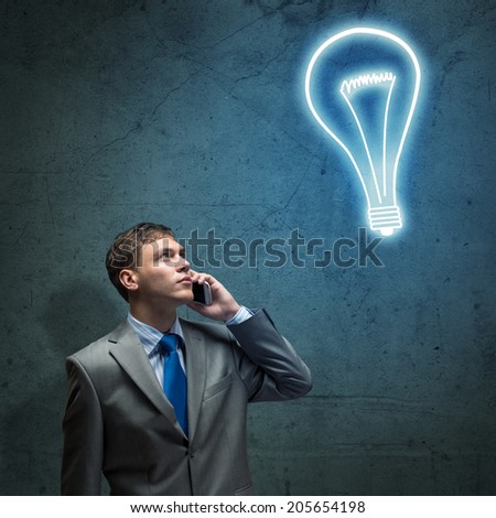 young businessman talking on cell phone and looking at the shining lamp