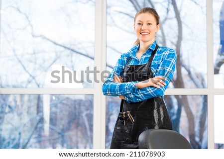 portrait of a woman in a barber shop barber worth apron crossed her arms