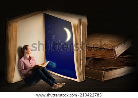 image of a young woman reading a book sitting near a big book