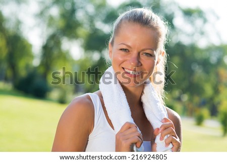 young attractive woman with a white towel around his neck, resting after sport exercises