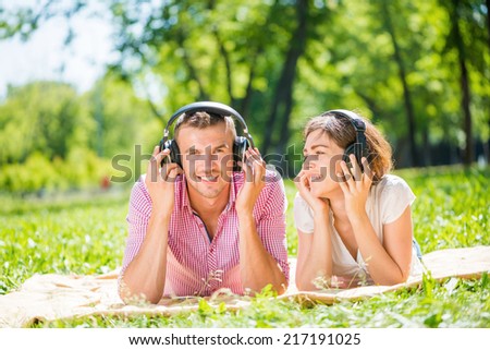 Young couple in summer park listening music