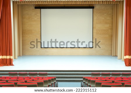 Image of cinema auditorium with blank screen and red seats