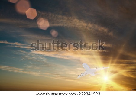 Airplane flying high in sky in beams of sunset
