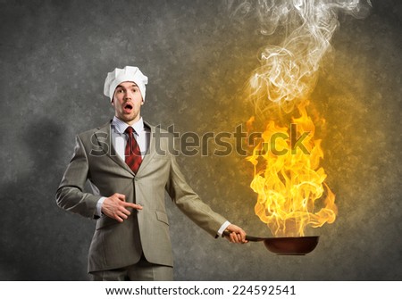 Young man in business suit and cook hat holding pan