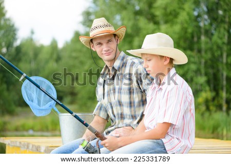 Father and son sitting on bridge and fishing