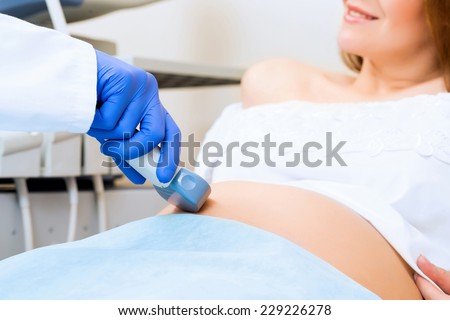 close-up of hands and abdominal ultrasound scanner for pregnant women