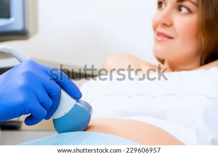close-up of hands and abdominal ultrasound scanner for pregnant women
