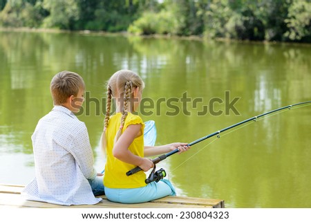 Back view of boy and girl sitting on wooden pier with rod