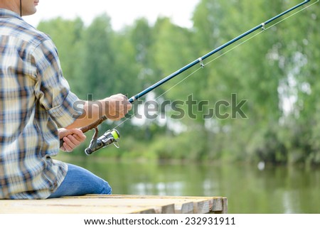 Close up of man sitting on pier with rod