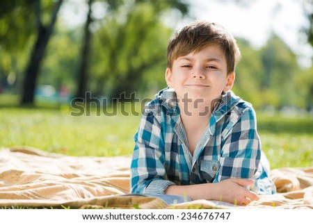 Cute boy in summer park lying on blanket