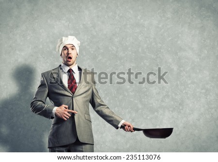 Handsome businessman wearing cook hat with pan in hands