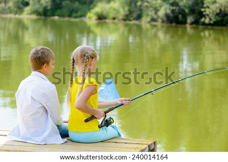 Back view of boy and girl sitting on wooden pier with rod