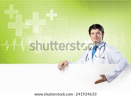 Young handsome doctor holding white blank banner. Place your text