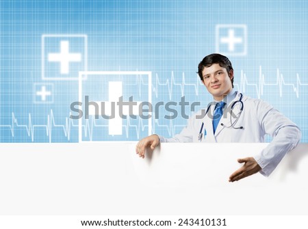 Young handsome doctor holding white blank banner. Place your text