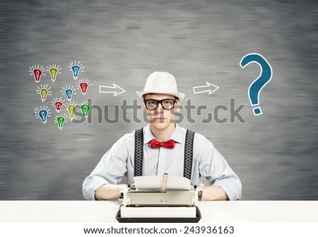 Young guy writer in hat and glasses using typing machine