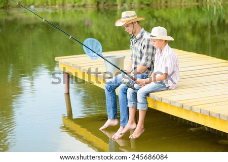 Father and son sitting on bridge and fishing