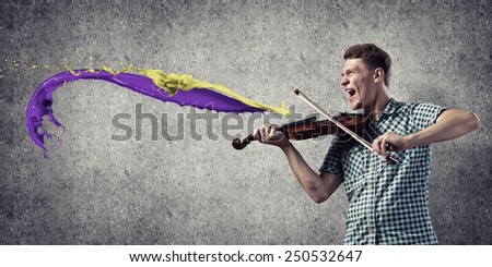Young handsome guy playing violin very emotionally