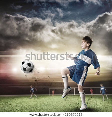 Excited boy football player at stadium kicking ball