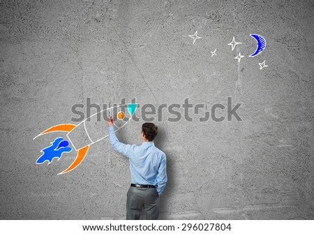 Rear view of businessman drawing rocket on wall