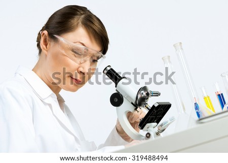 Attractive female scientist looking at the microscope slide in laboratory