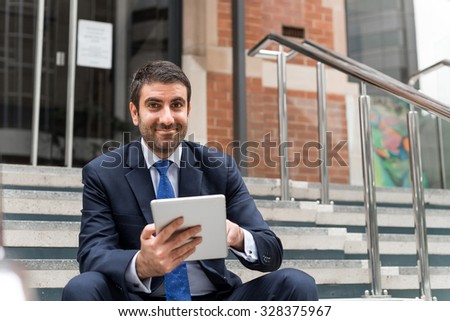 Handsome businessman sitting on steps with tablet pc