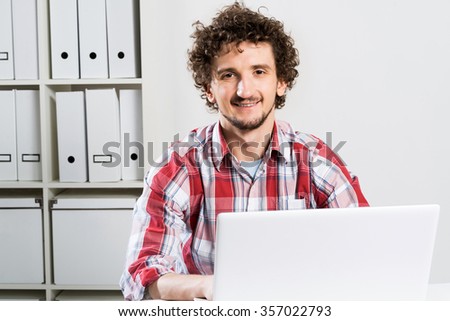 Young man in checked shirt typing on his notebook