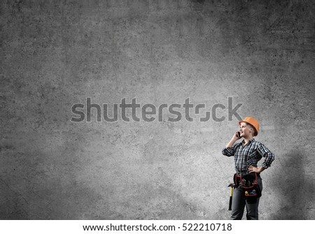 Engineer woman talking mobile phone against concrete wall background