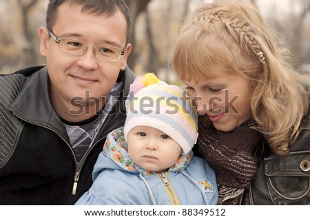 The young family in park, sits on a ground