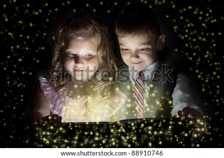 The boy and the girl hold the book, christmas lights around fly