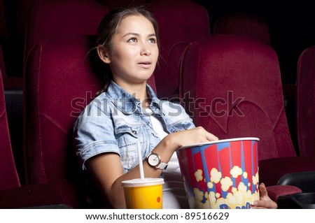 young woman sitting alone in the cinema and watching a movie