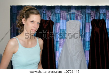 Bride with her dress and bridesmaids dresses hanging behind her
