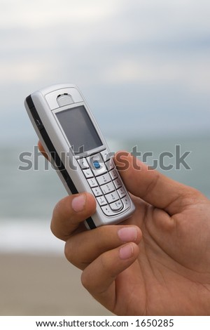 Close up of a cell phone with the sea as a defocused background