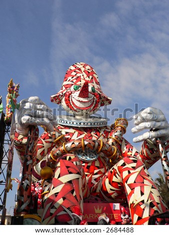 the typical mask of Viareggio carnival represented here in a cart and some masked people