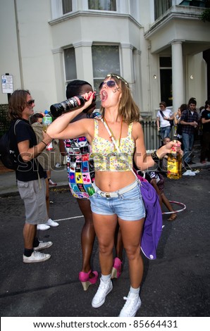 LONDON - AUG 28: girl drinks and dance in the street  of the Notting Hill during the annual caribbean Carnival on August 29, 2011 in London, England.