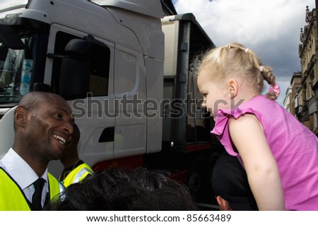 LONDON - AUG 28: black security man smiles at an unidentified blonde child during the  Notting Hill Carnival on August 29, 2011 in London, England. The annual carnival,  has been one of the safest in the history.