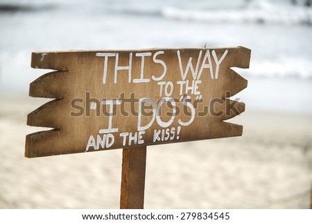 Wedding sign on driftwood in front of blue ocean