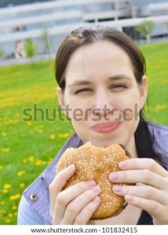 Happy beautuful girl eating hamburger.