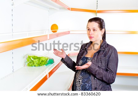 Young woman leans against empty shelves in shop