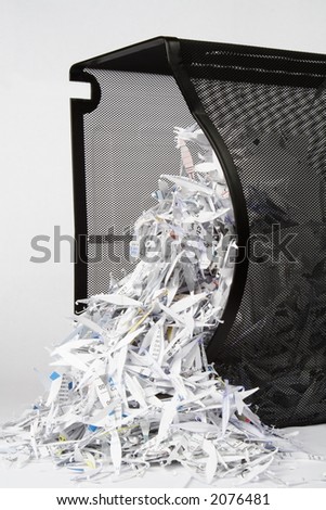 A spilled over paper shredder waste basket