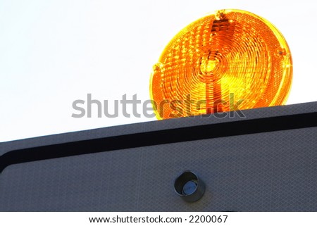Yellow warning flashing light on top of road hazard sign