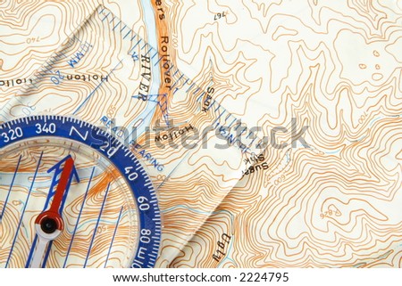 Low angle view of a compass on a topographic map pointing to a river