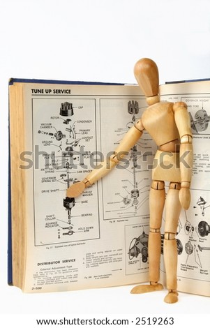 A wooden person teaching about a car repair from a technical manual