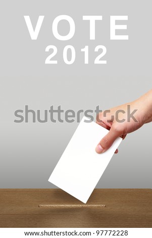 Hand putting a voting ballot in a slot of wooden box on white