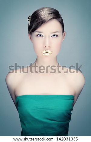 Studio photo of a young woman with bright make-up and gold lips
