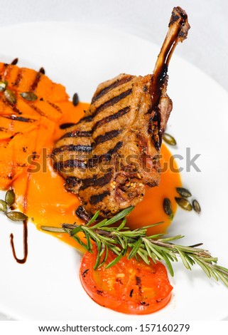 Veal on the bone. Grilled meat ribs on white plate with tomatoes and sauce in pumpkin